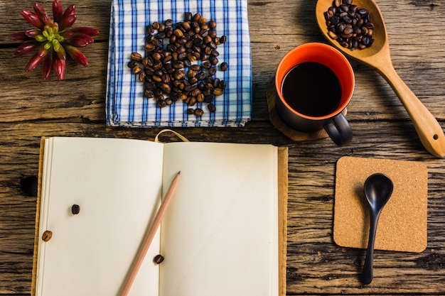 Draufsicht, Röstkaffeebohnen, Kaffee und Anmerkungen auf dem Holztisch.