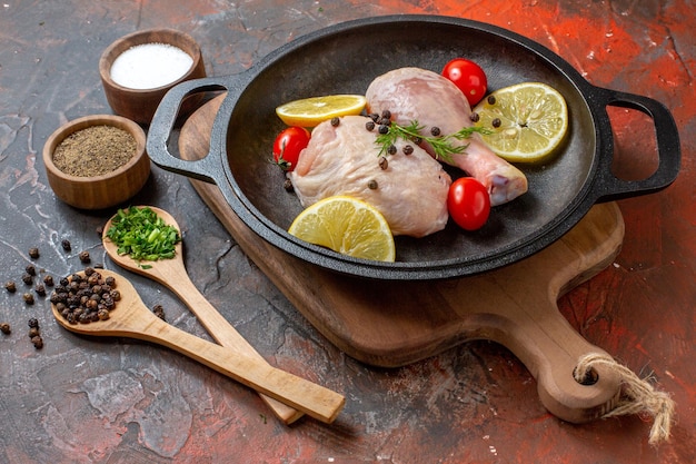 Draufsicht rohes Huhn mit Zitrone und Kirschtomaten in der Pfanne auf dunklem Hintergrund Küche Essen Fleisch Gemüse Farbe Gericht