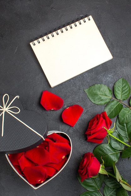 Draufsicht rote rosen mit schachtel voller rosenblätter zum valentinstag auf dunklem hintergrund liebe frau herz paar farbe leidenschaftsgefühl