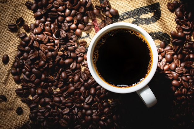 Foto draufsicht schwarzer kaffee in der weißen keramischen kaffeetasse mit röstkaffee