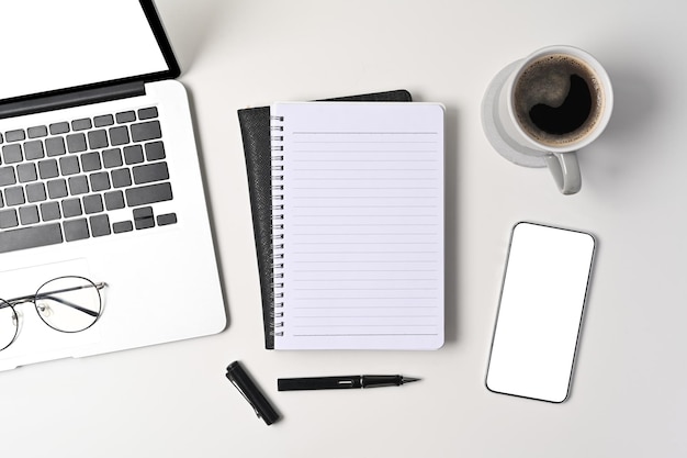 Draufsicht Smartphone Laptop Computer Notebook und Kaffeetasse auf weißem Tisch