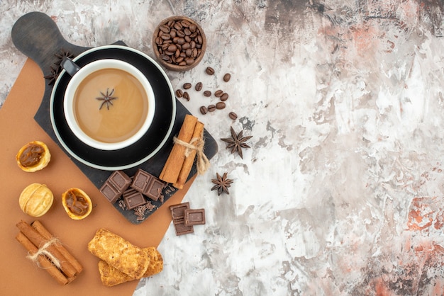 Draufsicht Tasse Kaffee Schokolade Zimtstangen Kekse auf Holzbrett geröstete Kaffeebohnen in Holzschale auf Tisch mit Kopierplatz