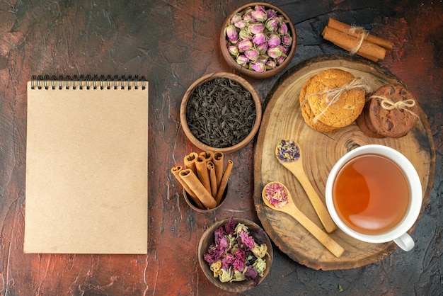 Draufsicht Tasse Tee mit Keksen und Blumen auf dunklem Hintergrund Geschmack Blumenfarbe Foto Tee Kaffee