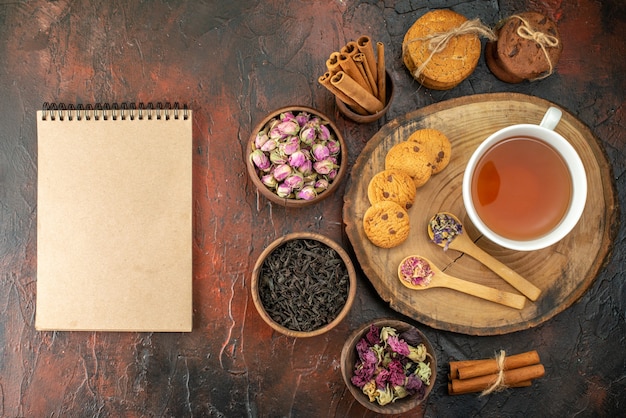 Draufsicht Tasse Tee mit Keksen und Blumen auf dunklem Hintergrund Geschmack Blumenfarbe Tee Kaffee Foto