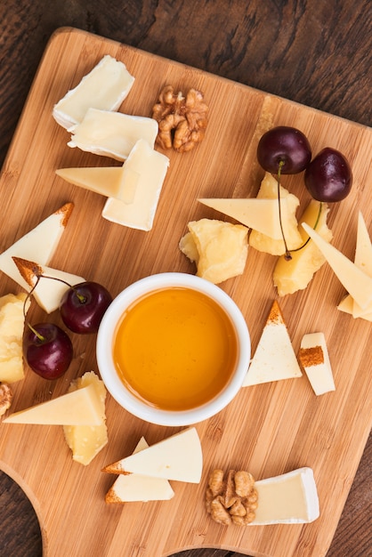 Draufsicht über Satz Käse Parmesankäse, Mozzarella, Camembert und eine Schale Olivenöl auf einem hölzernen Brett
