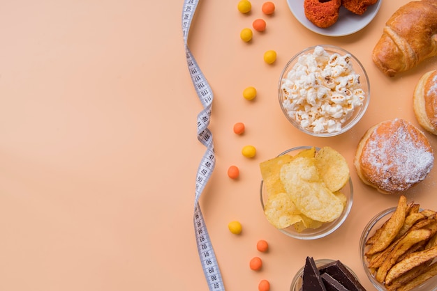 Draufsicht ungesunde Snacks und Maßband mit Kopierraum