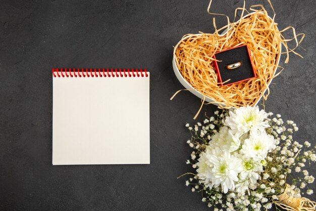 Draufsicht Verlobungsring in Box weiße Blumen Notizbuch auf Tisch