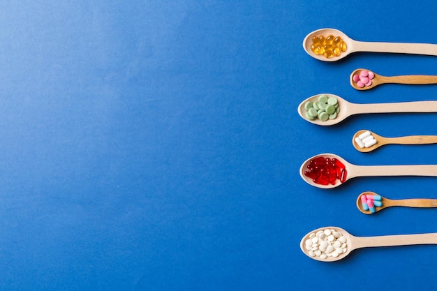 Draufsicht Verschiedene Vitamin- und Mineralpillen in Holzlöffel auf farbigem Hintergrund Draufsicht auf verschiedene pharmazeutische Medizinpillen Nahrungsergänzungsmittel Gesundheitsprodukt