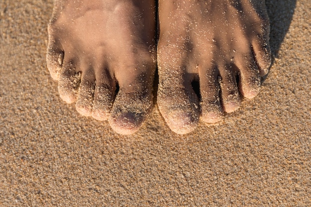 Draufsicht von bloßen Füßen auf Sand