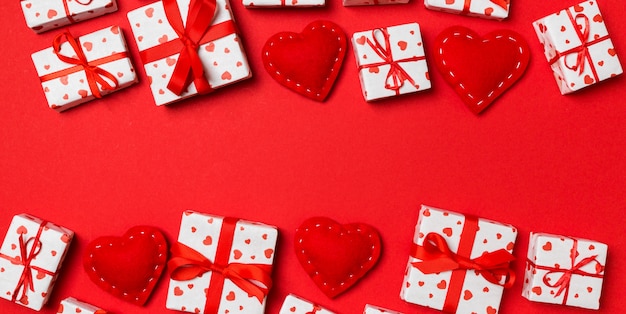 Draufsicht von festlichen Geschenkboxen und von roten Textilherzen auf buntem mit copyspace. Valentinstag