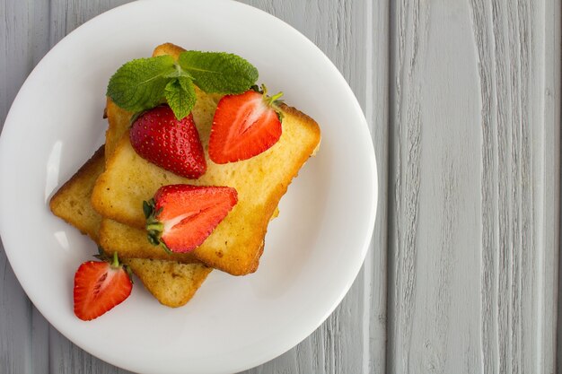 Draufsicht von French Toast mit Erdbeeren in der weißen Platte auf der grauen Oberfläche