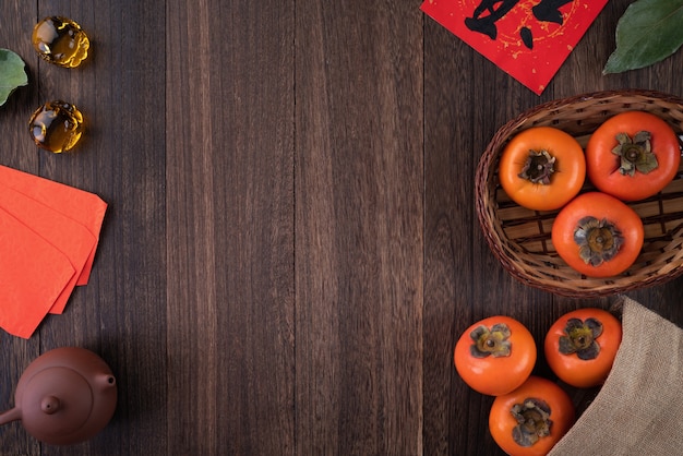 Draufsicht von frischem süßem Kaki-Kaki mit Blättern auf Holztisch für chinesisches Mondneujahrskonzept, das Wort bedeutet Segen kommt.