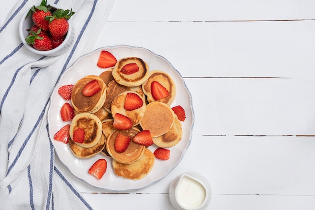 Foto draufsicht von mini-pfannkuchen mit erdbeeren auf weißem holztisch