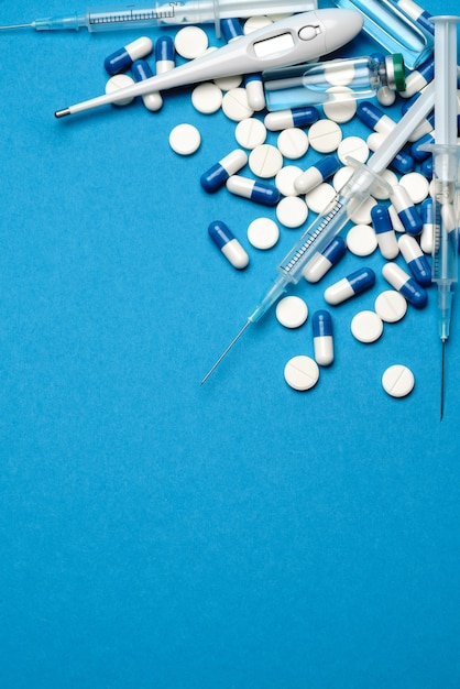 Draufsicht von Pillen, Spritze, Thermometer und Ampulle mit Impfung Auf blauem Hintergrund mit Kopie