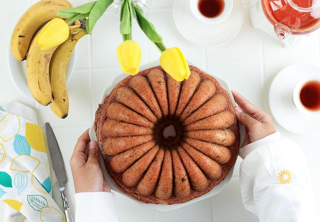 Draufsicht Weibliche Hand halten große Platte mit Bananen-Bundt-Brot-Kuchen