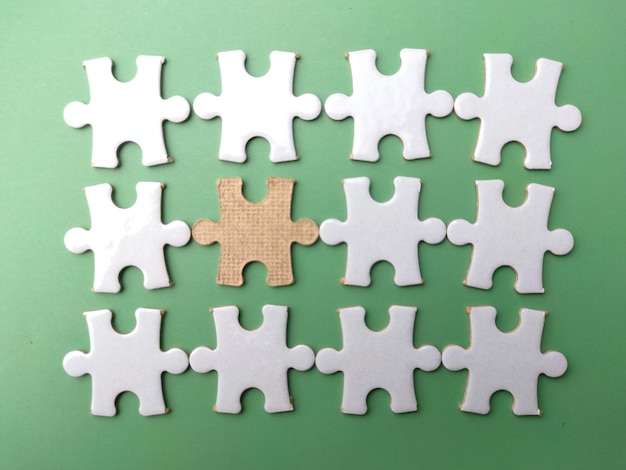 Draufsicht weißes Puzzle mit dem braunen Puzzle auf grünem Hintergrund Das Konzept des Kopierraums