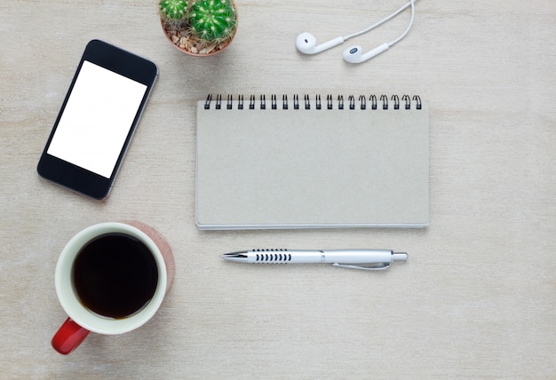 Draufsicht Zubehör Büro Schreibtisch das Handy, beachten Papier, Stift, Kaffee, Kopfhörer auf hölzernen Büro Schreibtisch Hintergrund.