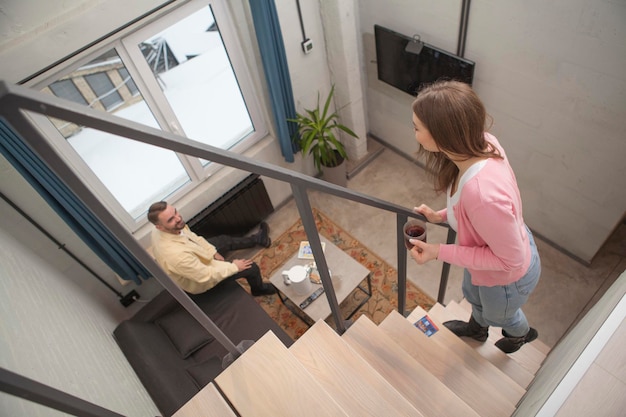 Draufsichtaufnahme einer Frau, die mit ihrem Partner spricht, während sie die Treppe eines Hotelzimmers hinaufgeht