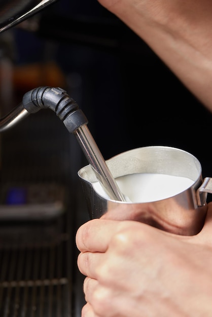 Foto draufsichtaufnahme eines professionellen baristas, der milch aus einem glas in eine tasse kaffee gießt kaffee wird vorbereitet