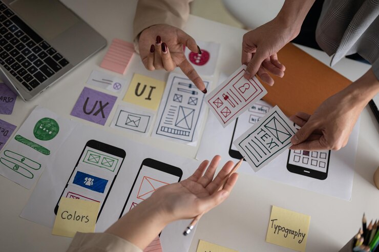 Foto draufsichtbild eines ux-ui-grafikdesignerteams, das im meeting über einen perfekten prototyp abstimmt