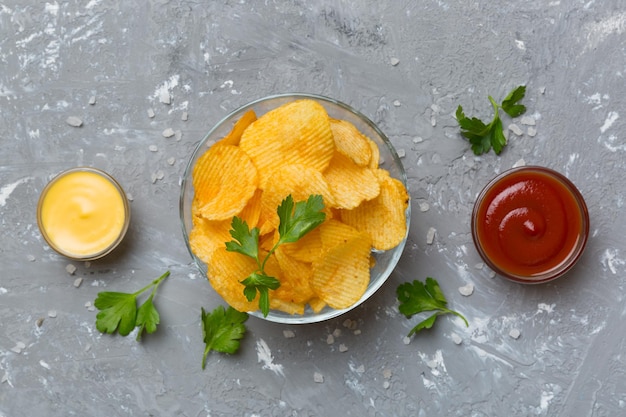 Draufsichtchips mit Soße in der Schüssel auf Draufsicht des farbigen Hintergrundes mit Kopienraum