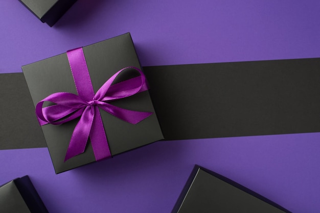 Draufsichtfoto einer schwarzen Geschenkbox mit lila Schleifenboxen auf isoliertem violettem und schwarzem Hintergrund mit Copyspace