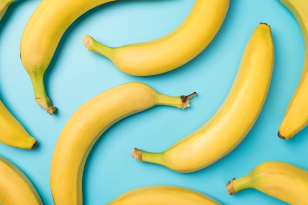 Draufsichtfoto von ungeschälten gelben Bananen auf isoliertem pastellblauem Hintergrund