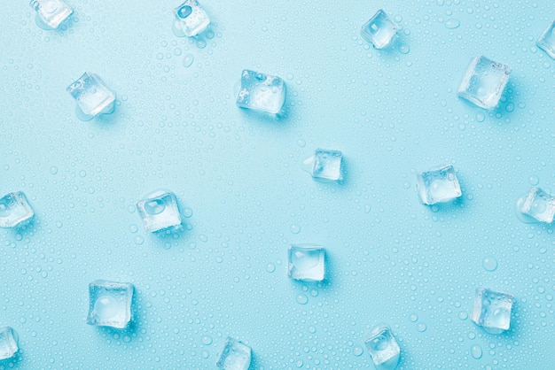 Draufsichtfoto von verstreuten schmelzenden Eiswürfeln und Wassertropfen auf isoliertem hellblauem Hintergrund