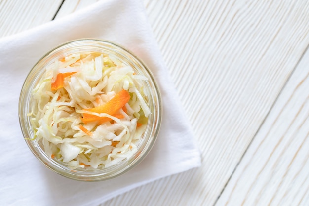 Draufsichtglasglas mit Sauerkraut auf weißem Tuch