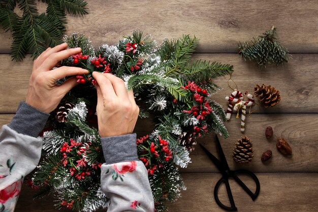 Foto draufsichthände, die weihnachtskranz verzieren