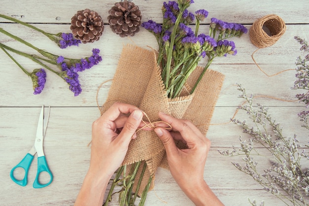 Draufsichthand des Frauenfloristen Blumenstrauß der Blume auf Tabellensystem herstellend