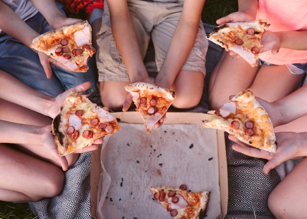 Draufsichtkinder, die eine Scheibe Pizza essen