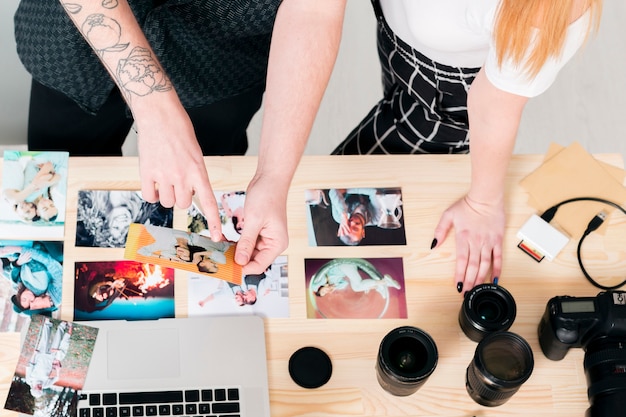 Draufsichtmann und -frau, die mit Fotos und Laptop arbeiten