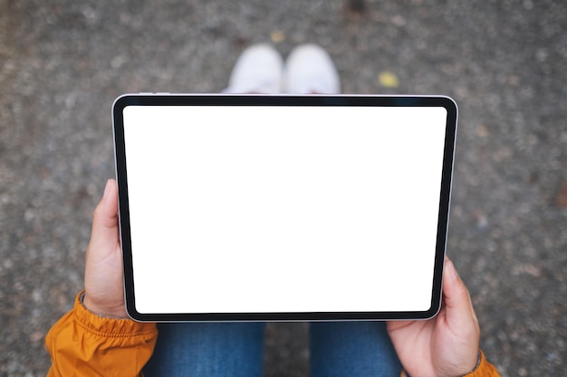 Draufsichtmodellbild einer Frau, die ein digitales Tablet mit einem leeren weißen Desktop-Bildschirm im Freien hält