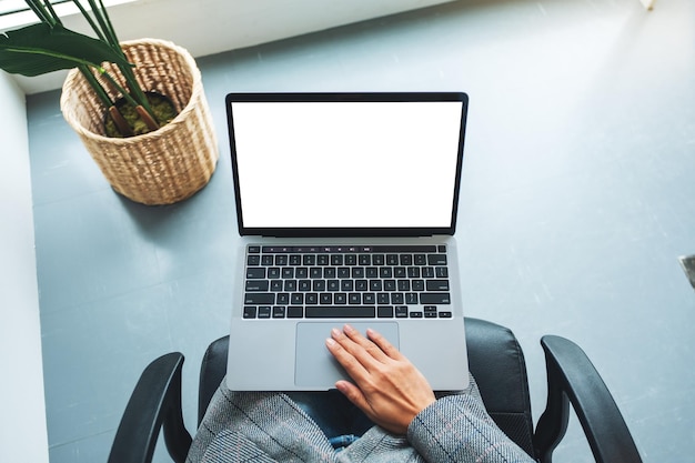 Draufsichtmodellbild einer Frau, die Laptop-Touchpad mit leerem weißem Desktop-Bildschirm im Büro verwendet und berührt