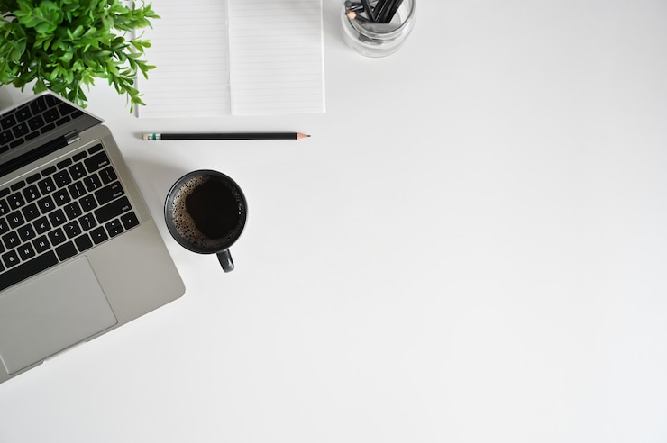 Foto draufsichtschreibtisch mit laptop, kaffeetasse, bleistift mit notizbuch auf kopienraum.