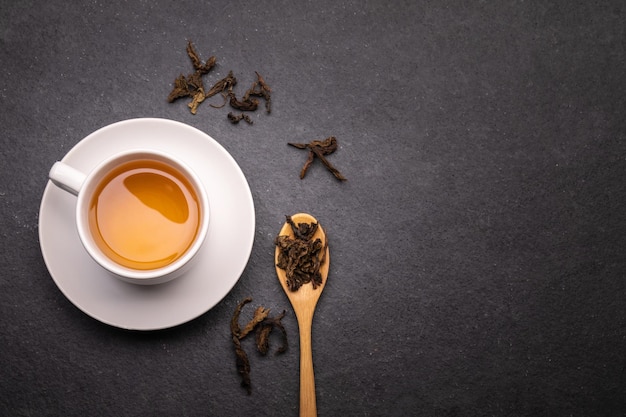 Draufsichttasse tee mit trockenem blatt auf schwarzem stein