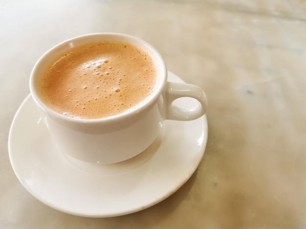 Draufsichttee mit Milch in einer Tasse, die im Volksmund als Teh Tarik auf dem Tisch bekannt ist.