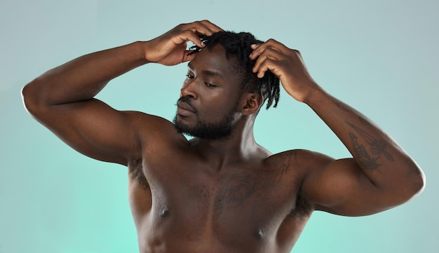 Dreadlocks cabelo homem sem camisa e estúdio para autocuidado de beleza e bem-estar cosmético por fundo azul modelo africano gen z músculo e corpo forte com as mãos na cabeça e massagem no couro cabeludo
