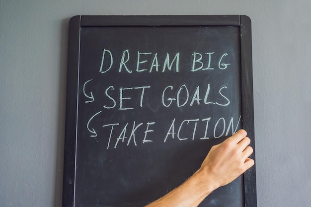 Dream Big Set Goal Take Action escritura a mano en una pizarra