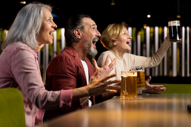 Drei ältere freunde trinken und jubeln in einem restaurant