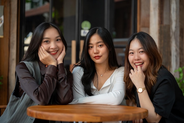 Drei attraktive junge asiatische Frauen sitzen zusammen an einem Tisch in einem Restaurant und verbringen viel Zeit miteinander.
