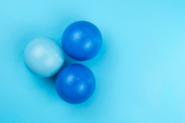 Drei Bälle in verschiedenen Kunststofftönen auf blauem Grund
