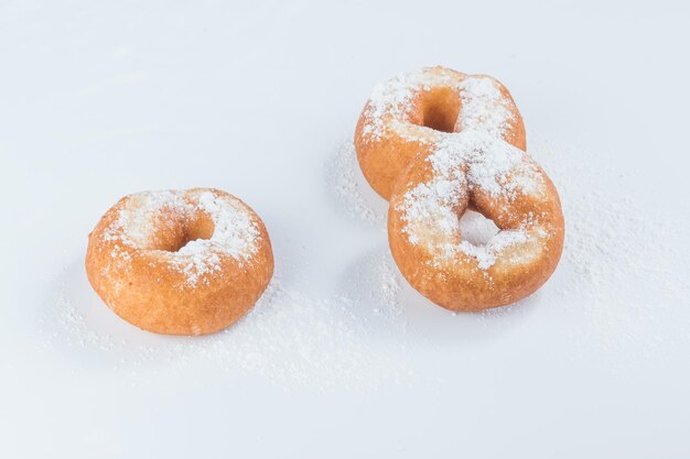 Drei Donuts mit Puderzucker auf hellem Hintergrund