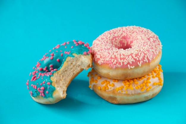 Drei Donuts mit whiteyellowpinkblue Glasur auf einem blauen Hintergrund süßes Dessert festlich