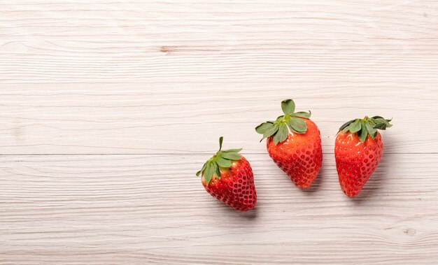 Drei Erdbeeren auf Holzhintergrund