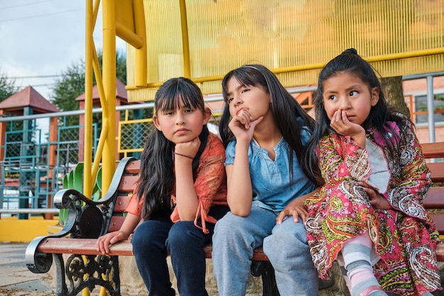 drei ernsthafte und nachdenkliche Mädchen sitzen in einem Park in Bolivien Lateinamerika