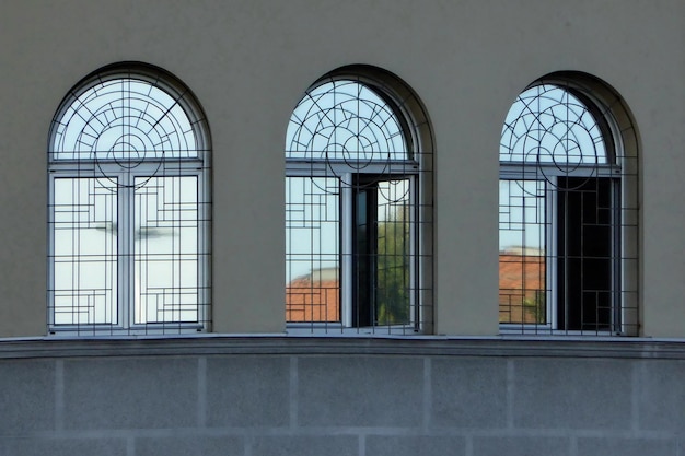 Drei Fenster mit Eisengitter auf grauer Wand