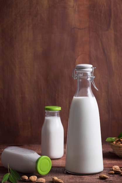 Drei Flaschen Mandelmilch auf einem braunen Holztisch