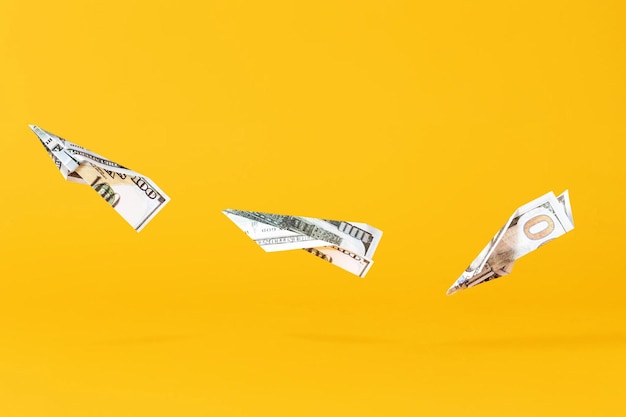 Drei Flugzeuge, die aus Dollargeld auf gelben Hintergrund fliegen